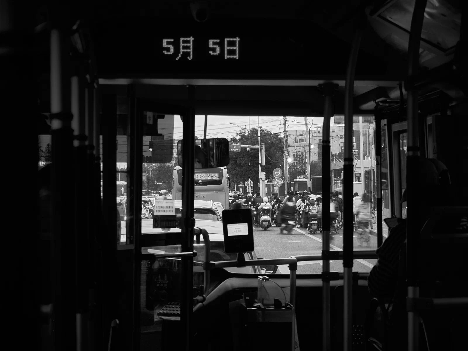 Crowds and cyclists seen ahead through the windscreen of a bus.