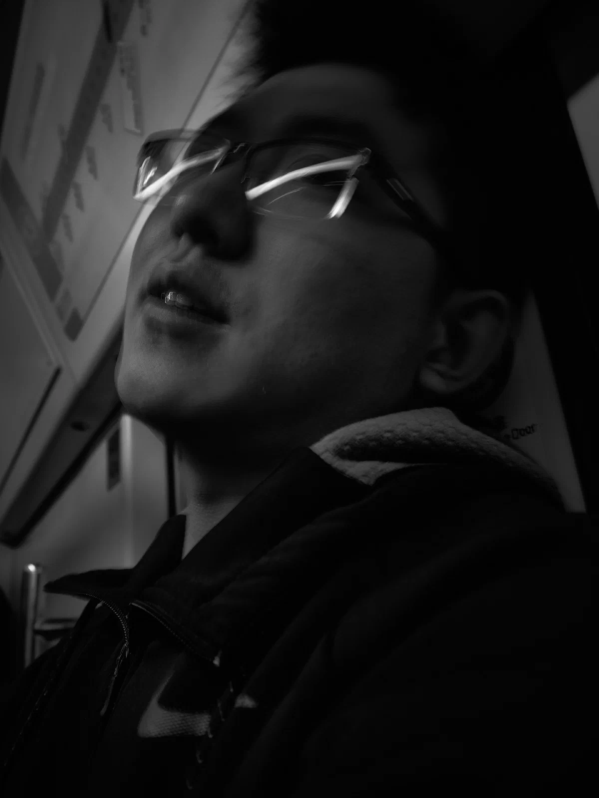 Close portrait of a man wearing glasses and an earbud inside a carriage.