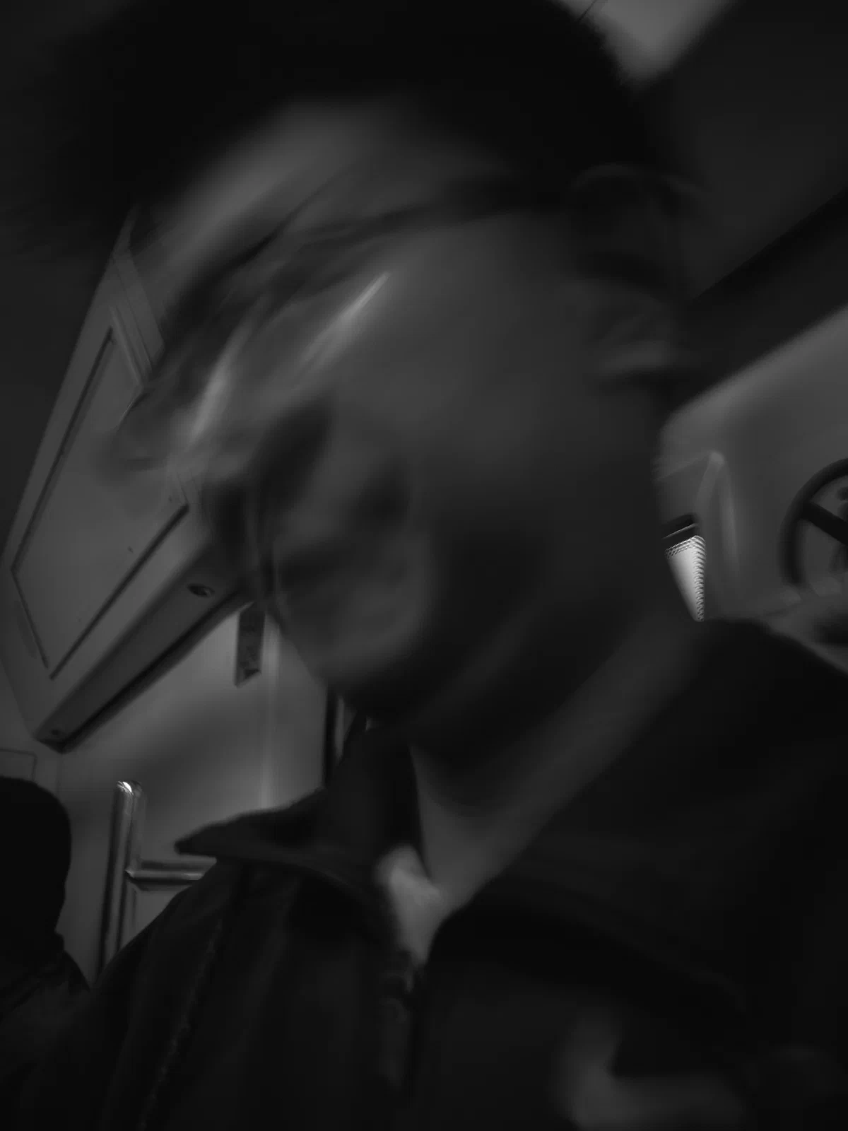 A man’s face blurred by movement inside a carriage.