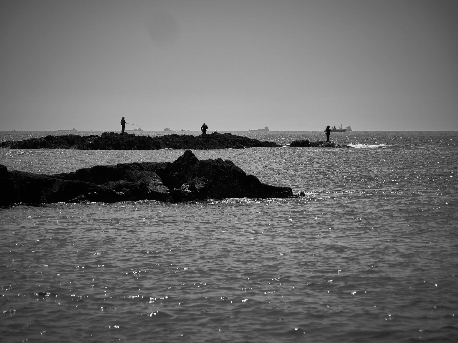 People fishing from rocks by the sea.